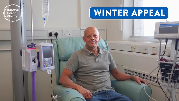 A bald man sat in a green chair next to a window. He is wearing a grey shirt and blue jeans. A machine is next to the chair on his left and above it is a bag containing clear liquid, which is attached to his arm with a clear tube. In the top left of the image is the Imperial Health Charity logo. In the top right is the title 'Winter Appeal' in white font on a blue background