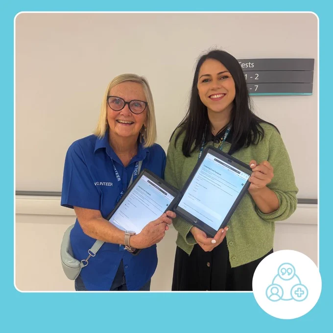 A photo of a volunteer and patient experience staff member at Broomfield hospital holding ipads conducting a listening event with in main outpatients
