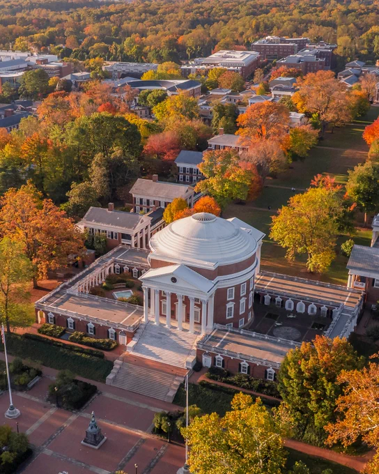 Aerial view of the University of Virginia Rotunda, surrounded by colorful autumn foliage and adjacent historic buildings.