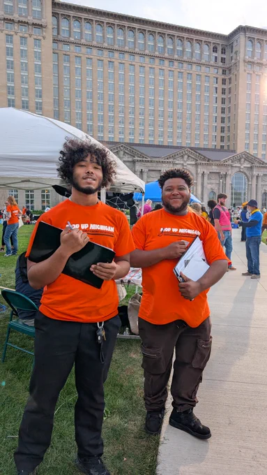 Mop Up Michigan circulators in orange shirts holding clipbaords in front of Michigan Central Station 