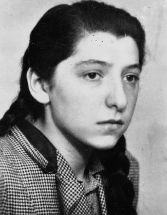 A portrait photo of a young girl with sad expression. She has dark long hair.