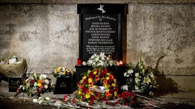 Flowers around a memorial plaque with names of the murdered victims outside the Rising Sun Pub in Greysteel