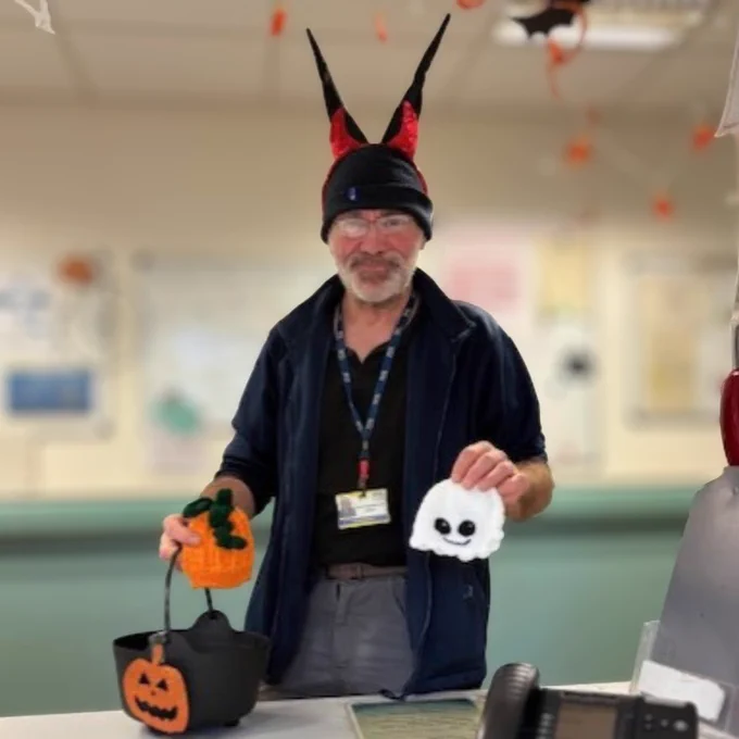 Pictured is a colleague holding two of the hats that have been made for babies.