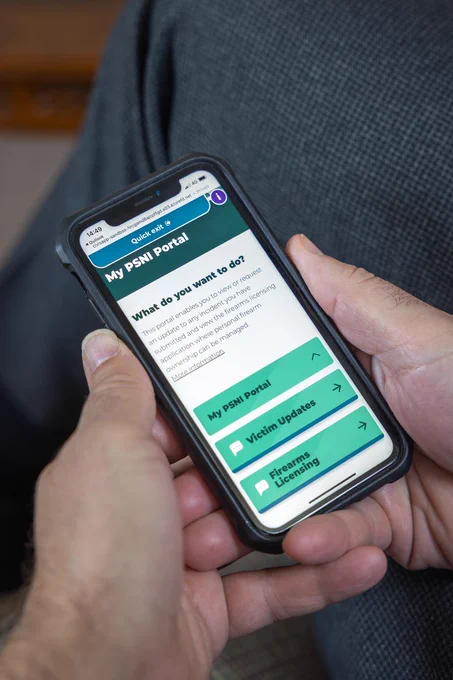 Man's hands holding a mobile phone showing the My PSNI Portal webpage