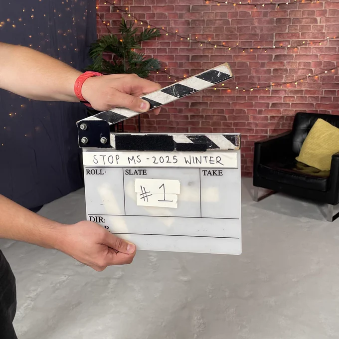 Two hands holding a clapperboard, used for filming. Written text on the clapperboard reads “Stop MS - 2025 Winter”
