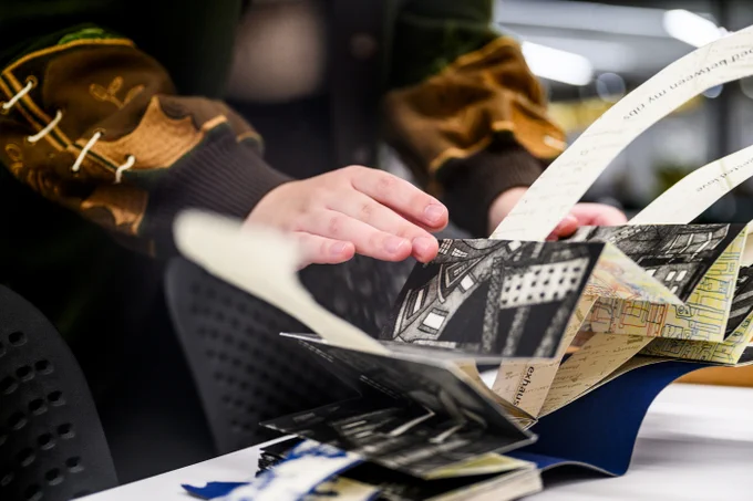 A close-up of a person's hands opening and unfolding an illustrated book