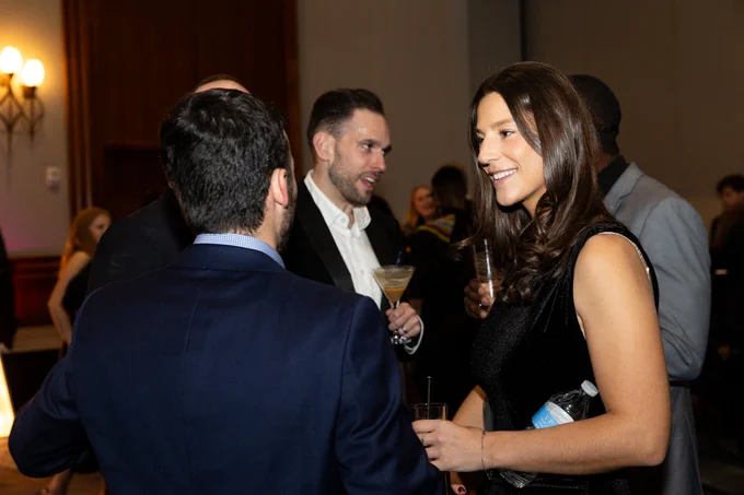 People in formal attire smile while in conversation