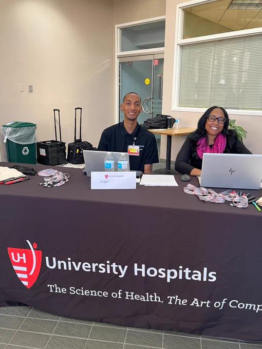 Brandon Taylor and Chiquita Bellamy with University Hospitals sit at their booth. University Hospitals logo.