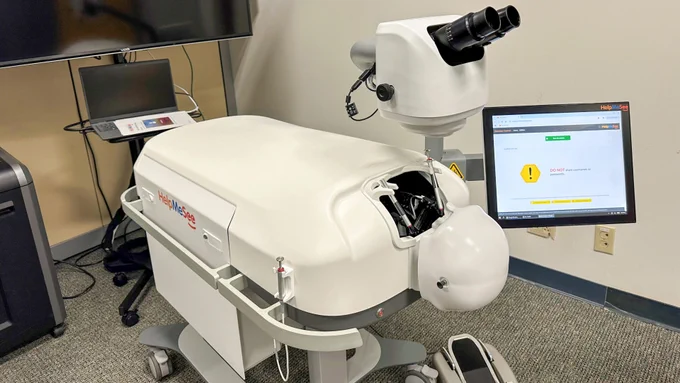 Image of an HelpMeSee Surgical Simulator in a clinical setting, positioned next to a computer monitor displaying test results.