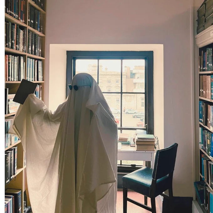 Library staff dressed as a ghost shelving a book