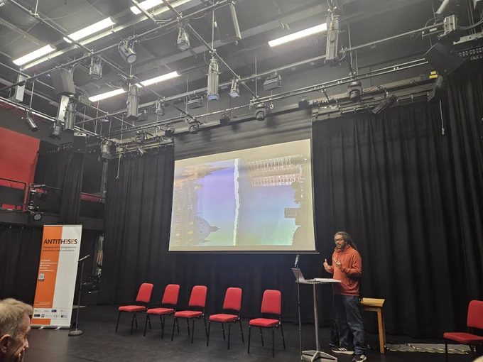 Photo of a person in front of a screen presenting their slide