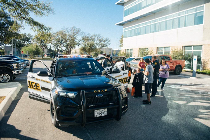 San Antonio City Police car parked outside a building with several individuals standing nearby.