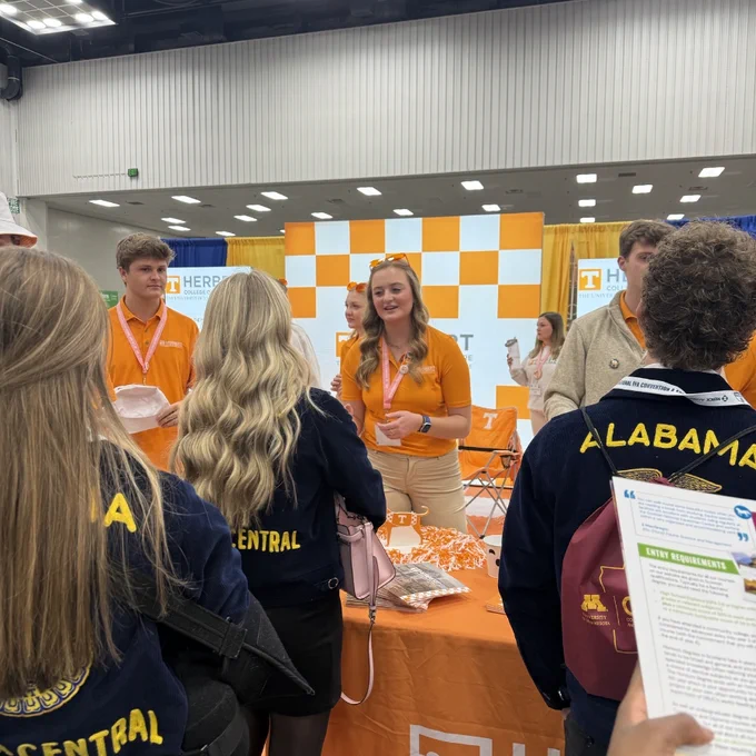 Group of individuals engaging at a University of Tennessee promotional booth during a convention.