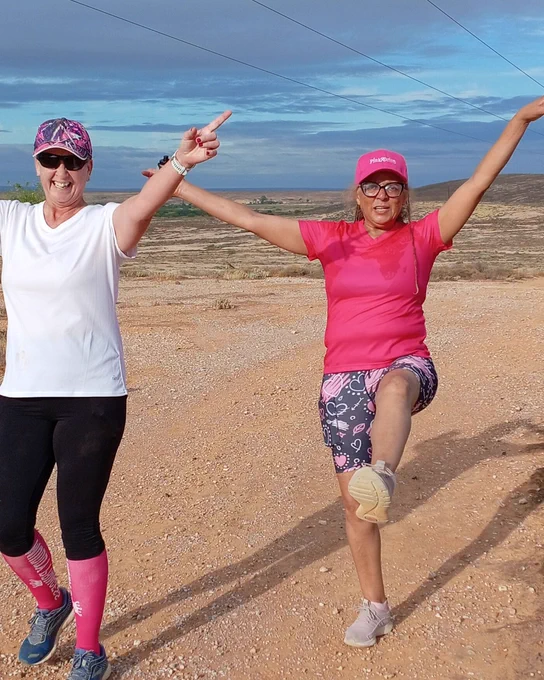 Two parkrunners on the beach smiling with their arms in the air!