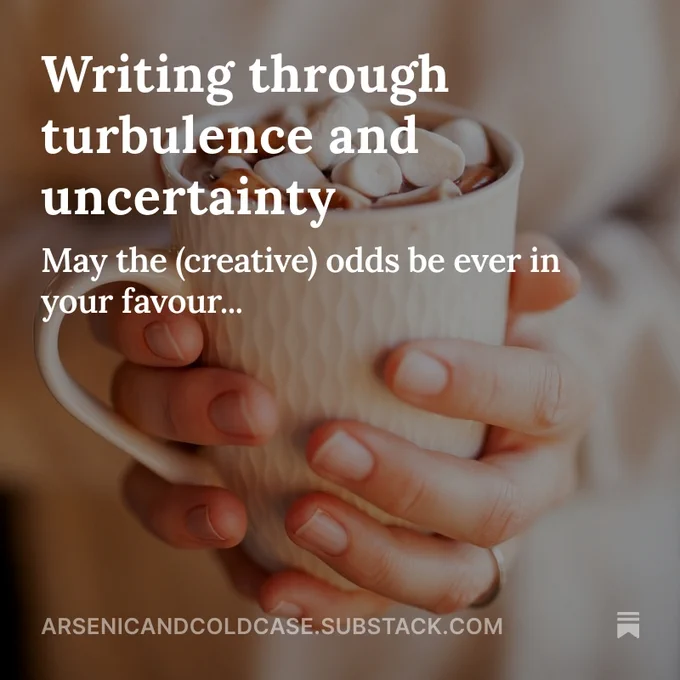 Image shows hands gently holding a textured cream mug containing hot chocolate that has been topped with many little marshmallows. The background is blurred neutral colours. Overlaid in white text is: Writing through turbulence and uncertainty; may the creative odds be ever in your favour.
