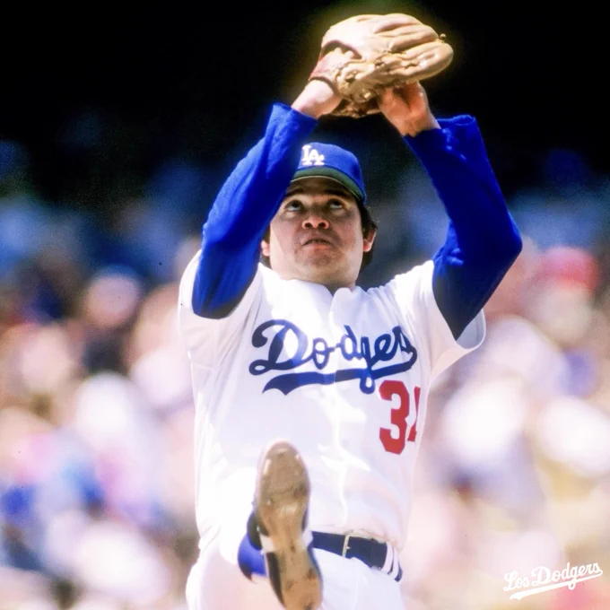 Una imagen de Fernando Valenzuela a punto de hacer un lanzamiento con sus brazos hacia arriba y la mirada al cielo.