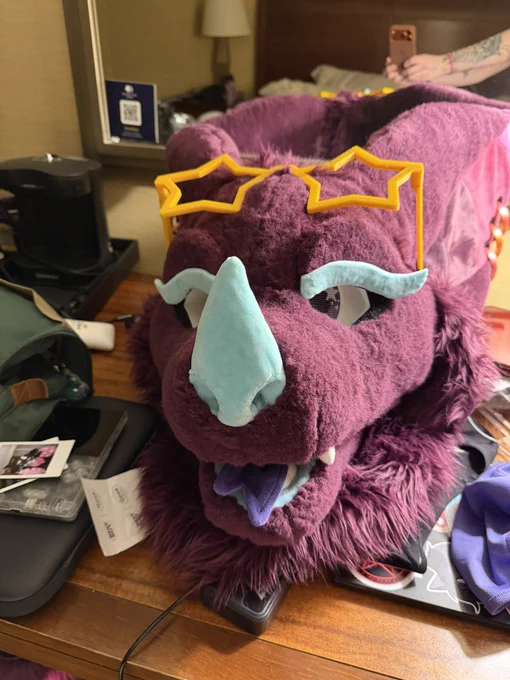fursuit head on a table with the star glasses resting on their head