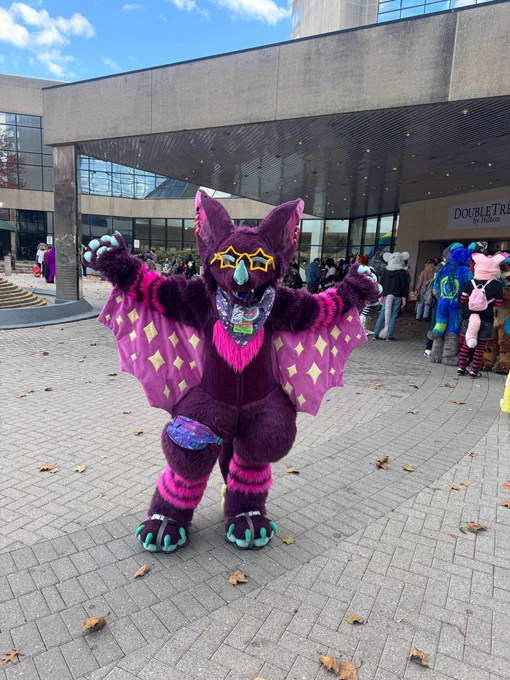 purple and pink bat character fursuit with star glasses posing