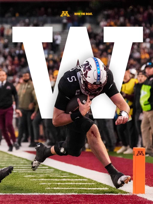 Drake Lindsey reaching for the end zone in Minnesota's win over Michigan State. There is a giant W behind Lindsey in the image along with Row the Boat and the Block M representing the athletics logo for the University of Minnesota - Twin Cities. 