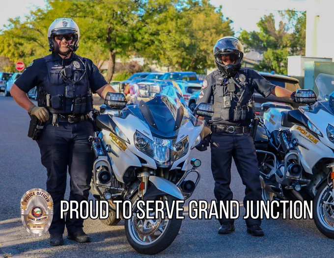 Two officers with helmets standing next to motorcycles