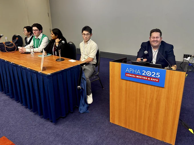 A person using a wheelchair is smiling while at a lowered speaker podium