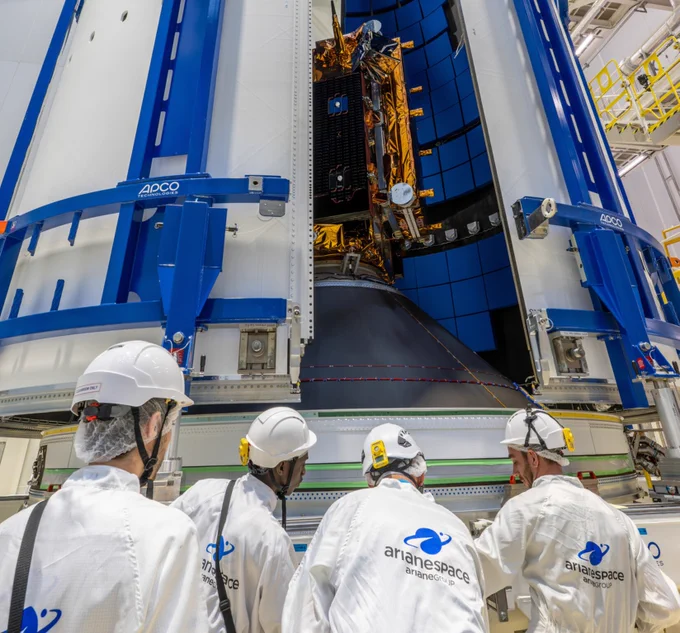 Four Arianespace technicians monitor the Copernicus Sentinel-1D satellite being encapsulated inside the Ariane 6 rocket fairing.