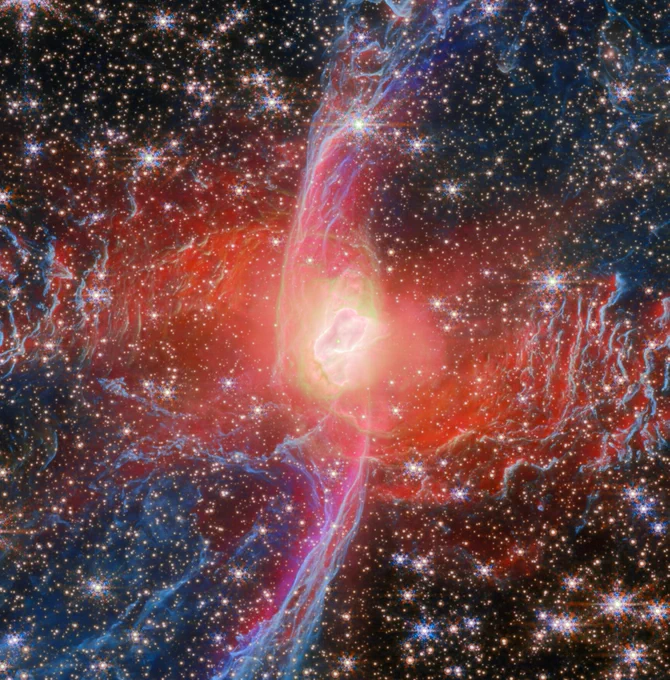 The Red Spider planetary nebula: the nebula’s central star is hidden by a blotchy pinkish cloud of dust. A strong red light radiates from this area, illuminating the nearby dust. 