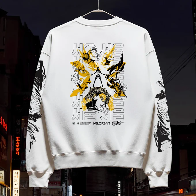 White sweatshirt with bold yellow-and-black artwork and text, hanging on a street at night.