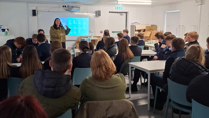 Person talking to a group of students and using a PowerPoint presentation.