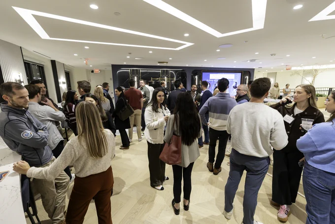Room full of event attendees stand mingling with one another