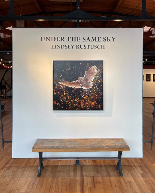 A gallery wall with the exhibition title Under the Same Sky above a framed painting of an owl in flight among leaves. Posted by Abend Gallery in Denver, Colorado, USA.