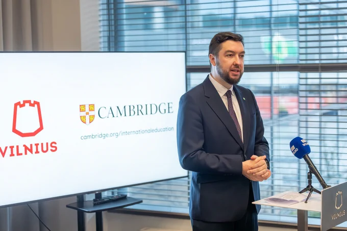 Deputy Mayor of Vilnius City Municipality, Vytautas Mitalas on stage at the podium with a TV on the background featuring Vilnius City's logo and the Cambridge International Education logo.