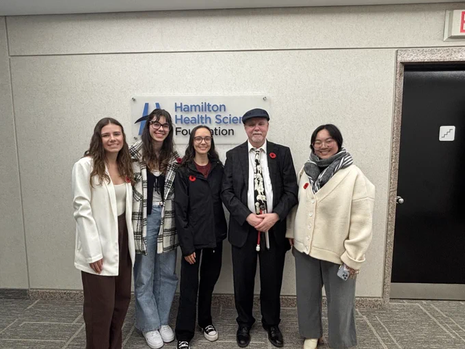 AHA! team members (left to right): Mya, Hannah, Ava, Tim, Enya stand in from of the Hamilton Health Sciences Foundation sign.
