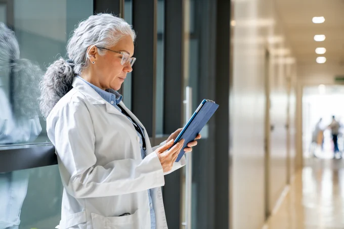 A physician uses a tablet to examine a patient's medical records.