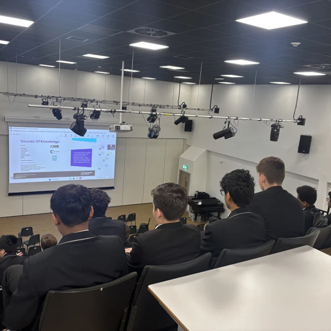 Key stage 4 and 5 students watching a presentation on a large screen from Rootshell Security.
