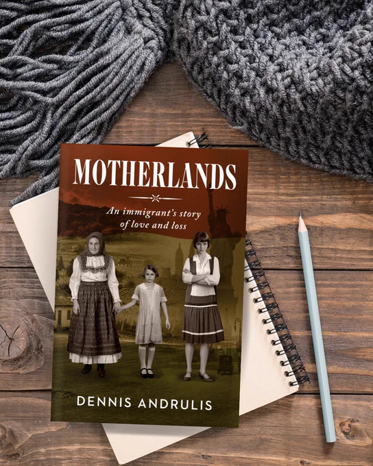 Motherlands by Dennis Andrulis on a wooden table with a gray blanket, notebook, and pencil