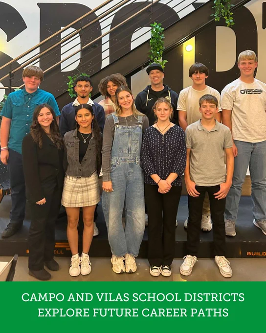 Group of students and a teacher from Campo and Vilas School Districts posing in front of a wall with a dynamic design, exploring future career paths.