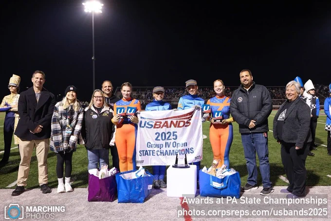 A group holding a "USBANDS 2025 Group IV Open STATE CHAMPIONS" banner on a football field at night.