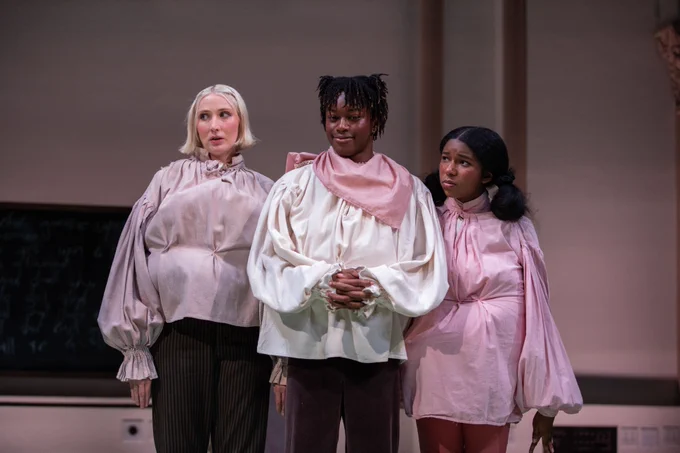 Three actors on stage during a theatrical performance, dressed in contemporary costumes .