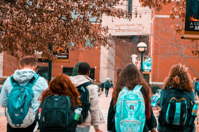 Image of 5 teenagers walking to college with backpacks on