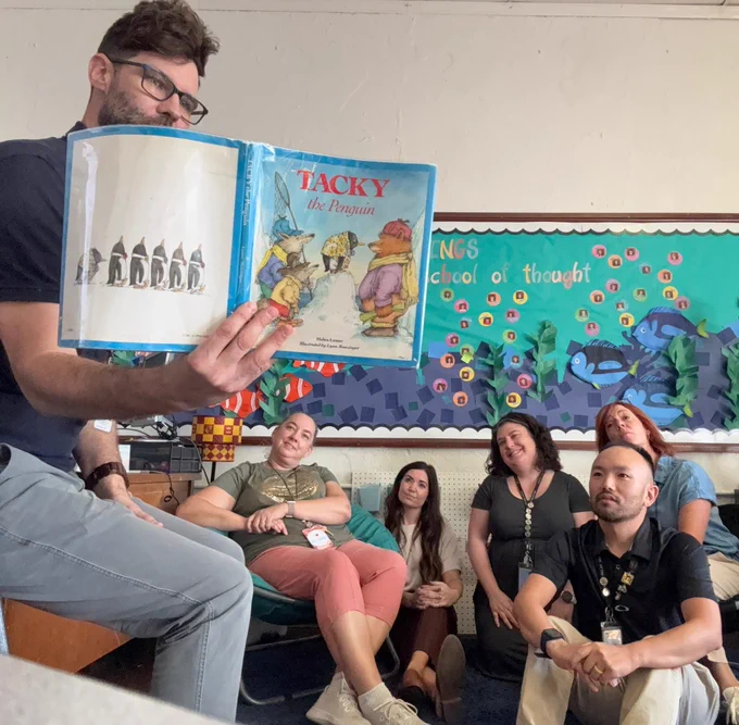 Man reading "Tacky the Penguin" picture book to a group of attentive adults