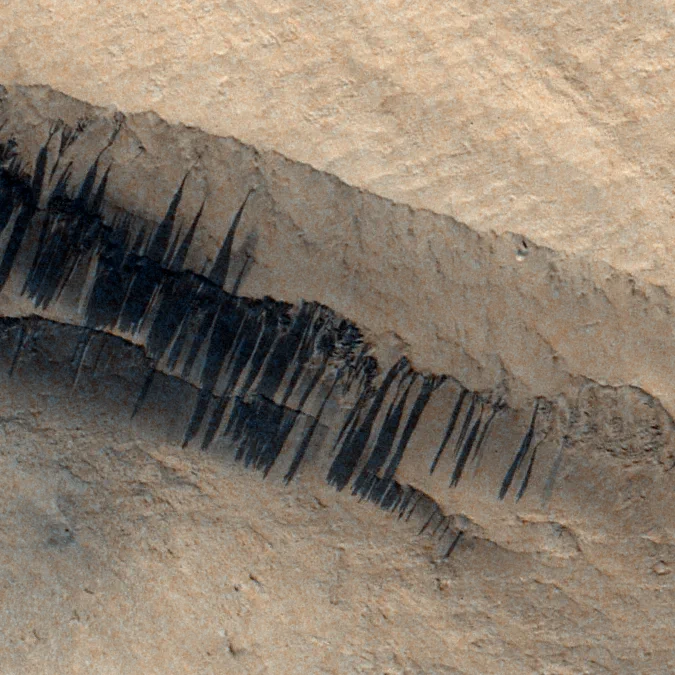 Dust avalanches on the slopes of a Martian ancient volcano, seen from above.