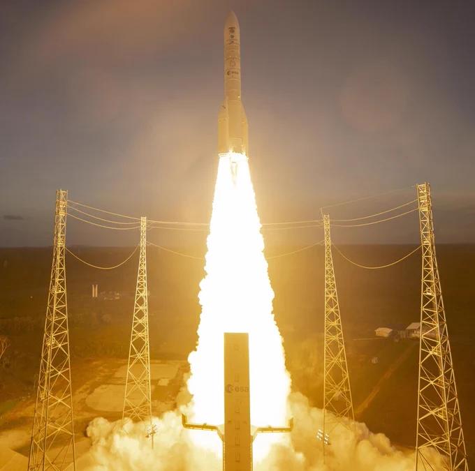 Ariane 6 lifting-off, projecting a trail of fire over the launch pad.