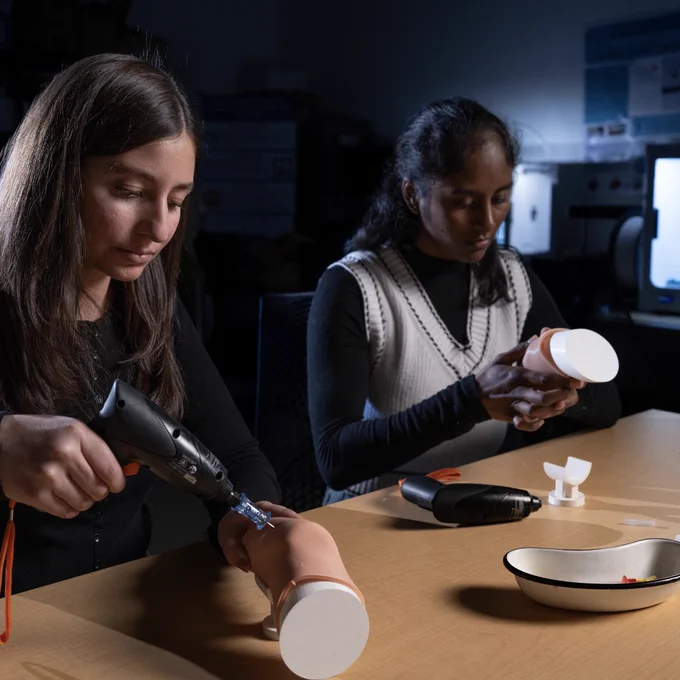 Two students working with lab tools and equipment inside a lab at Ontario Tech’s north campus. The student on the left is using a small drill.