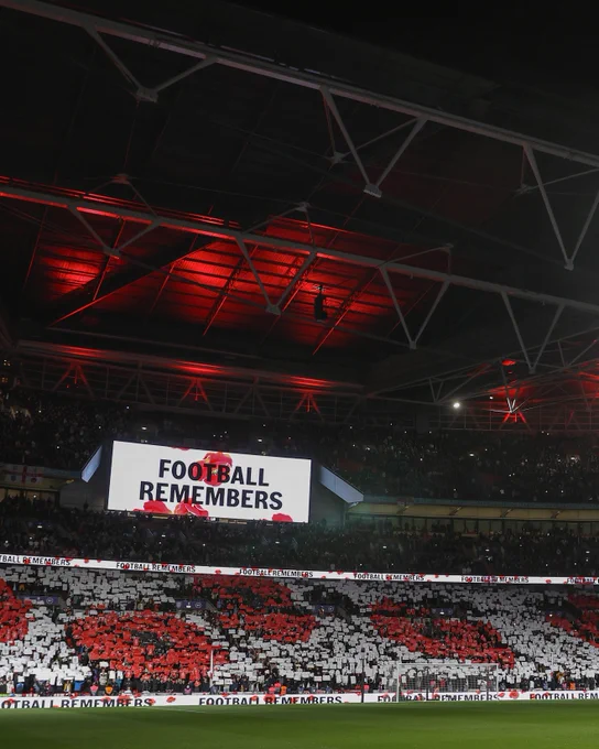 Inside Wembley Stadium as the LED screen displays a 'Football Remembers' message and fans hold up cards to create a pattern of poppies 