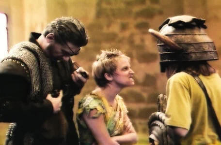 The cavern-elf Elita (Stephanie Hesp) glares at a helmeted dungeoneer in Knightmare Series 6 (1992). Behind her, Skarkill the Goblin Master (Rayner Bourton) prepares his shakles to capture the contestant.
