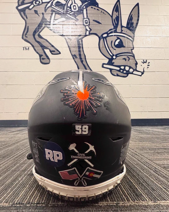 The back of a Mines football helmet with a circular "RP" sticker added to it