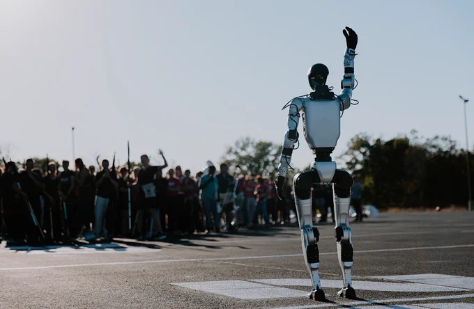 A robot waves to a group of people