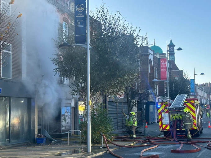 Smoke coming from a building, with firefighters and fire engine nearby