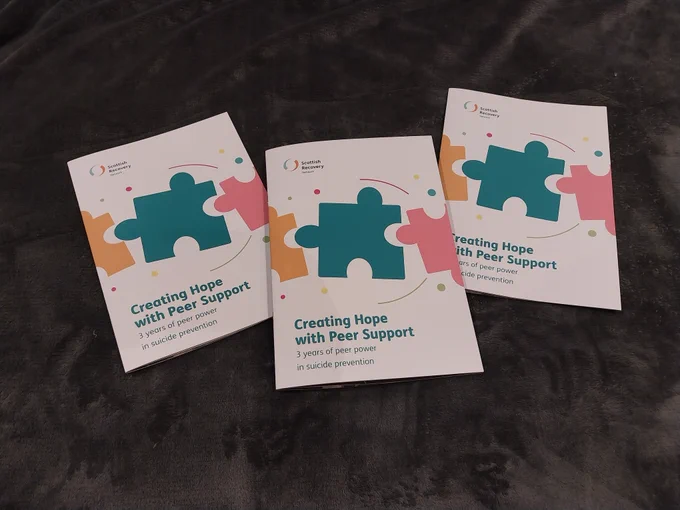 3 copies of the creating Hope with Peer Support report on a black backdrop.